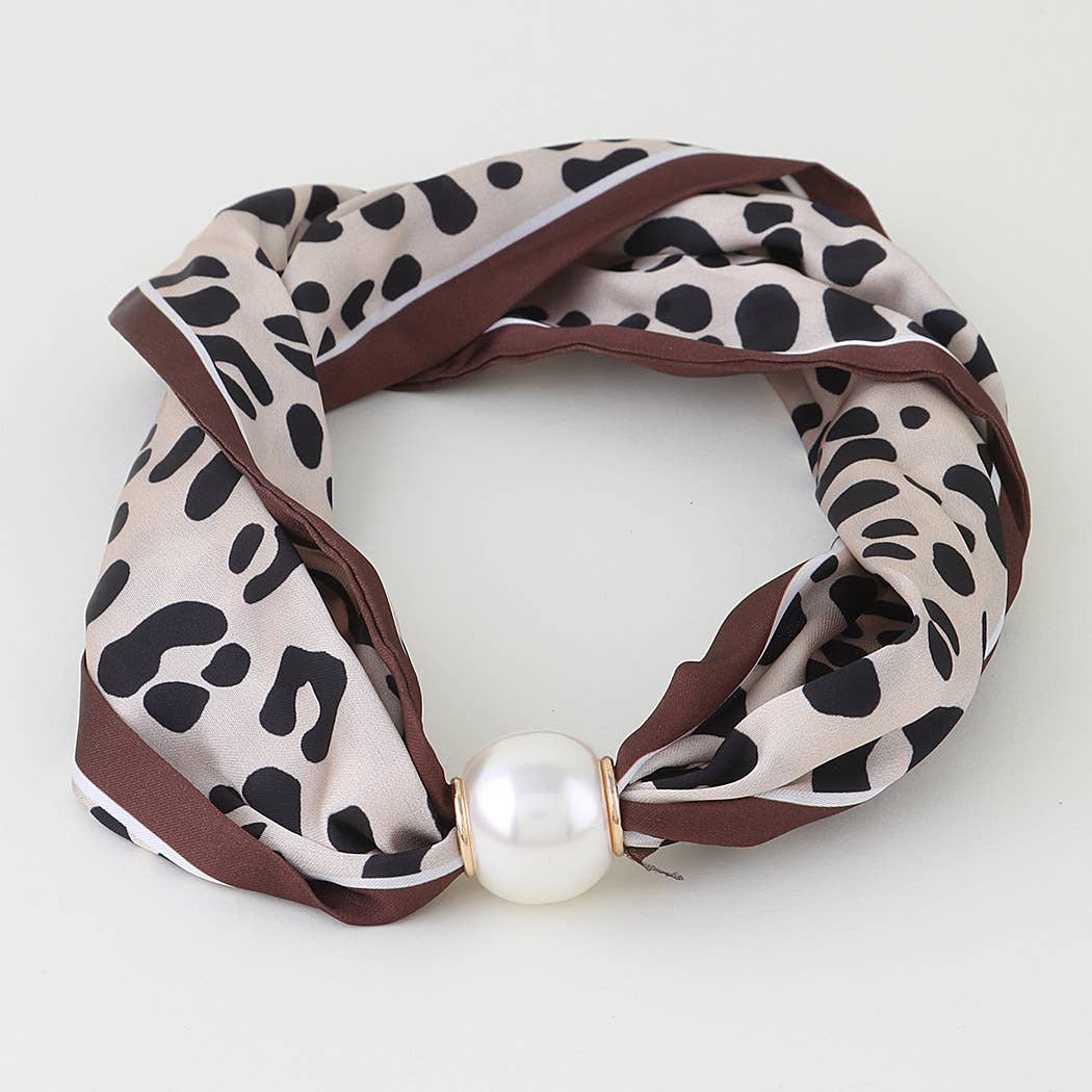 A leopard print silk scarf with brown trim and a large white faux pearl at the center, displayed on a clean white background.